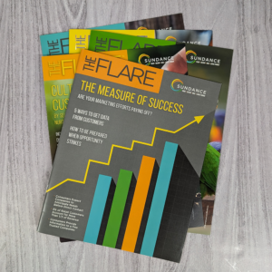 Splayed flat lay of five issues of SunDance magazine The Flare