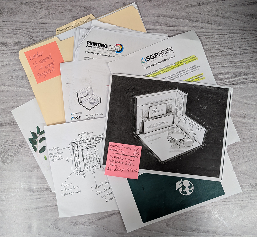 A display of a folder and numerous sketches and designs for a 100% recyclable tradeshow booth